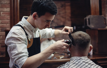 Barber shaves the client's head with a shaving machine.