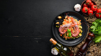 Bulgur with shrimp, mussels and vegetables. On the old background. Top view. Free space for your...