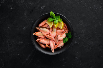 Shrimp with lemon in a plate on a black background. Top view. Free copy space.