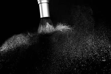 white powder splash and brush for makeup artist or beauty blogger in black background