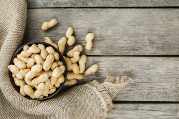 Peanuts in the shell, in a wooden cup on the table.