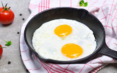 Delicious fried eggs in a cast iron pan. Top view of eggs and bread, breakfast scene.