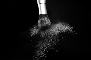 white powder splash and brush for makeup artist or beauty blogger in black background