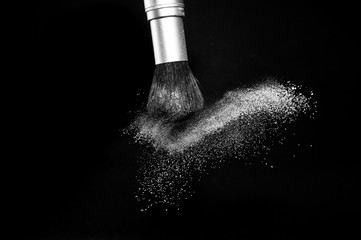 white powder splash and brush for makeup artist or beauty blogger in black background