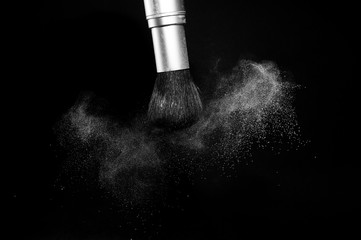 white powder splash and brush for makeup artist or beauty blogger in black background