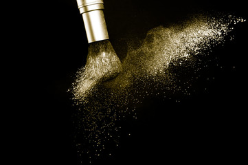 gold powder splash and brush for makeup artist or beauty blogger in black background, look like a luxury