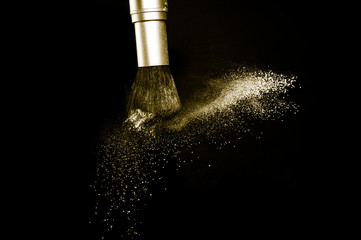 gold powder splash and brush for makeup artist or beauty blogger in black background, look like a luxury