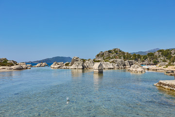 Fototapeta na wymiar Coast of the island in the Mediterranean sea, picturesque with the ruins of ancient Lycian towns and tombs-sarcophagi of Aperlai, Simena Teimussa Dolihiste.