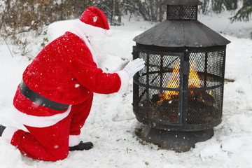 Père Noël a froid il se réchauffe les mains près du foyer