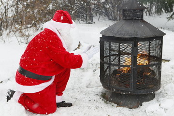 le Père Noël se réchauffe les mains près du foyer