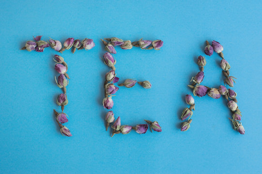Fototapeta Word Tea made from dried rose buds. Rose tea on blue background. Food lettering