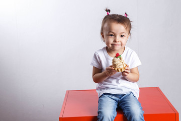 Little beautiful girl eating a cake with strawberry and creme