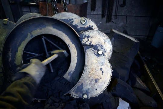 Arbeiter mit Hammer bearbeitet Metall Guss Form