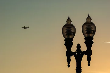 Fototapeten Vintage street lamp silhouette at sunset, city of Los Angeles, passenger aircraft in the distance © Gabriel Cassan