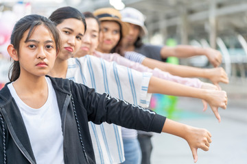Large group of people showing thumbs down.,Thinking sad friends. ,Dislike sign. Portrait team leader young teenage girl giving  thumbs down gesture looking with negative expression and disapproval.