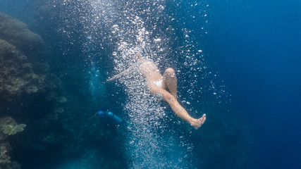Woman in bikini plays with scuba bubbles underwater