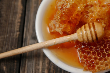 Honey with honeycomb in a white ceramic plate on rustic wooden table