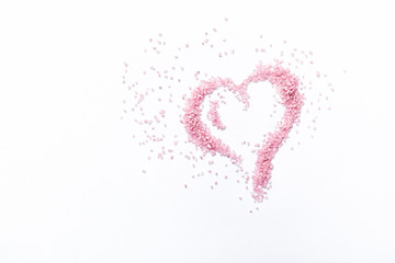 Abstract shape of heart made with pink sugar. Flatylay. Valentine's day concept. Copy space. White background