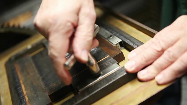 A man uses a quoin key to secure a block of type into a chase