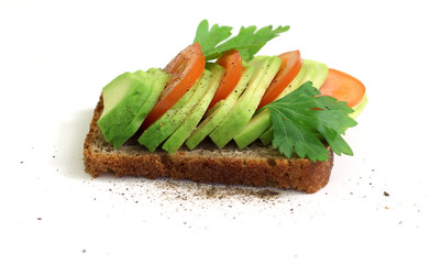 Avocado sandwich with tomato and seasoning on dark rye bread.