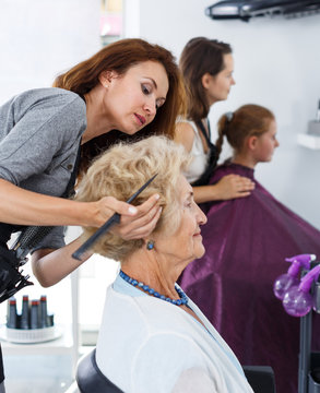Stylist doing hairdress for senior lady