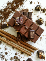 Different varieties of chocolate, chocolate tubes and cocoa on a white table