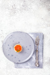 Holidays composition. Red Salmon Caviar in tartlet on a plate. Festive Appetizer  on  gray background.Copy space for Text.