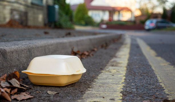 Discarded food container in gutter by the side of the road