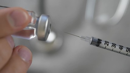Health doctor dials the vaccine into a syringe with needle - Powered by Adobe