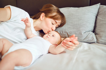 Mother playing with baby on the bed. 