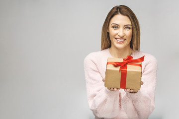 Fototapeta premium Image of Happy brunette woman in casual holding gift box and looking at the camera isolated over white background.