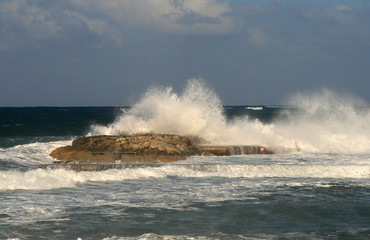 Fototapeta na wymiar Large waves breaking on a rock by the Mediterranean sea coast