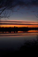 Croatia, nature park Lonjsko polje, beautiful red sunset over Sava river in autumn, reflection on water