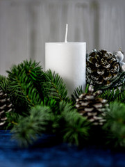 White candle with Christmas tree and pinecone on a blue background