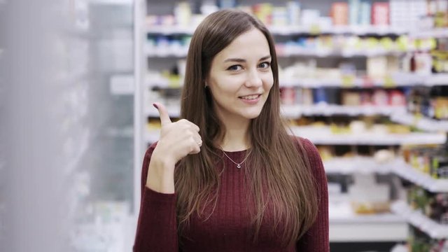Portrait of beautiful woman doing ok sign with fingers, excellent symbol in supermarket