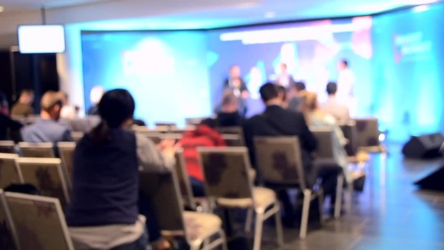 Blurred Background. Many people are sitting in the hall audience listening to presentation lecture speech at forum or conference. Neon lights