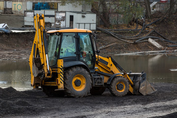 Big excavator during earthmoving works outdoors at construction site. Yellow excavator clears the river bed for the device pond. All-Russian exhibition center, Moscow. Russian Federation.