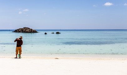 Maldivian native cleaning a beach of white sand and turquoise water