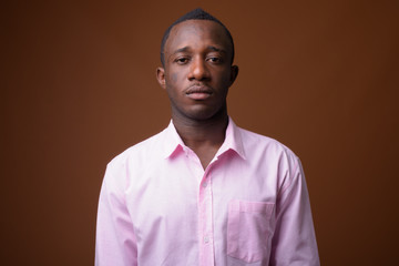 Obraz premium Portrait of young African businessman against brown background