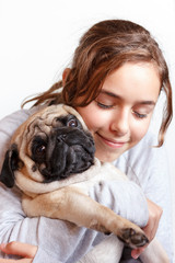Happy pretty smiling teenager girl hugging pug dog with love
