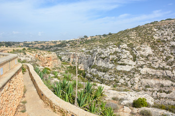 Fototapeta premium Famous natural limestone arch of the Blue Grotto and phosphorescent colours of the flora, Blue Grotto is a number of sea caverns on the south coast on Malta, Europe.
