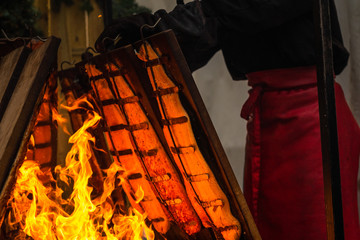 Der Grillmeister richtet die Holzbretter, auf denen Flammlachs am Feuer gegart wird