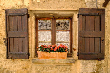 Façade d'une maison en Provence, France. Fenêtre avec des volets en bois, bac avec des fleurs.
