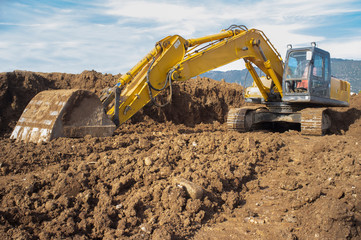 Earthmoving excavator preparing the construction site soil