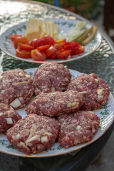 Raw pork and beef meat prepared for hamburgers on white rounded cutting board