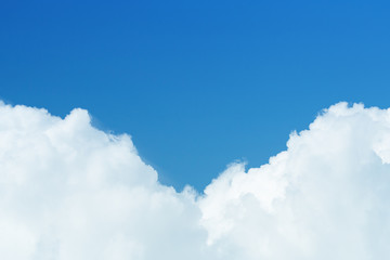 Close up view on a white cumulus fluffy clouds against a bright blue sky with copy space (background)