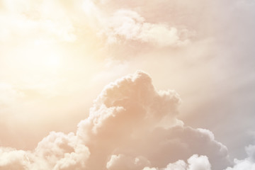 Soft cumulus fluffy clouds illuminated by the sun against a orange sky (background, toned) - obrazy, fototapety, plakaty