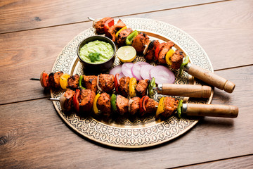 Chicken tikka /skew Kebab. Traditional Indian dish cooked on charcoal and flame, seasoned & colourfully garnished. served with green chutney and salad. selective focus