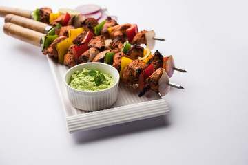 Chicken tikka /skew Kebab. Traditional Indian dish cooked on charcoal and flame, seasoned & colourfully garnished. served with green chutney and salad. selective focus