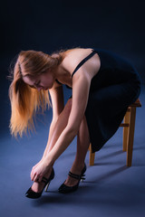 Slender attractive girl sitting on a stool trying on shoes